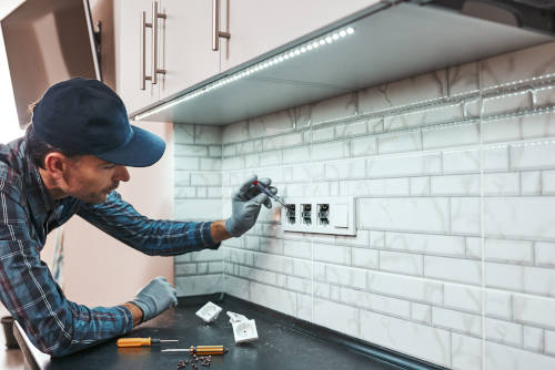 All is safe. Side view of young handyman setting new sockets at the kitchen